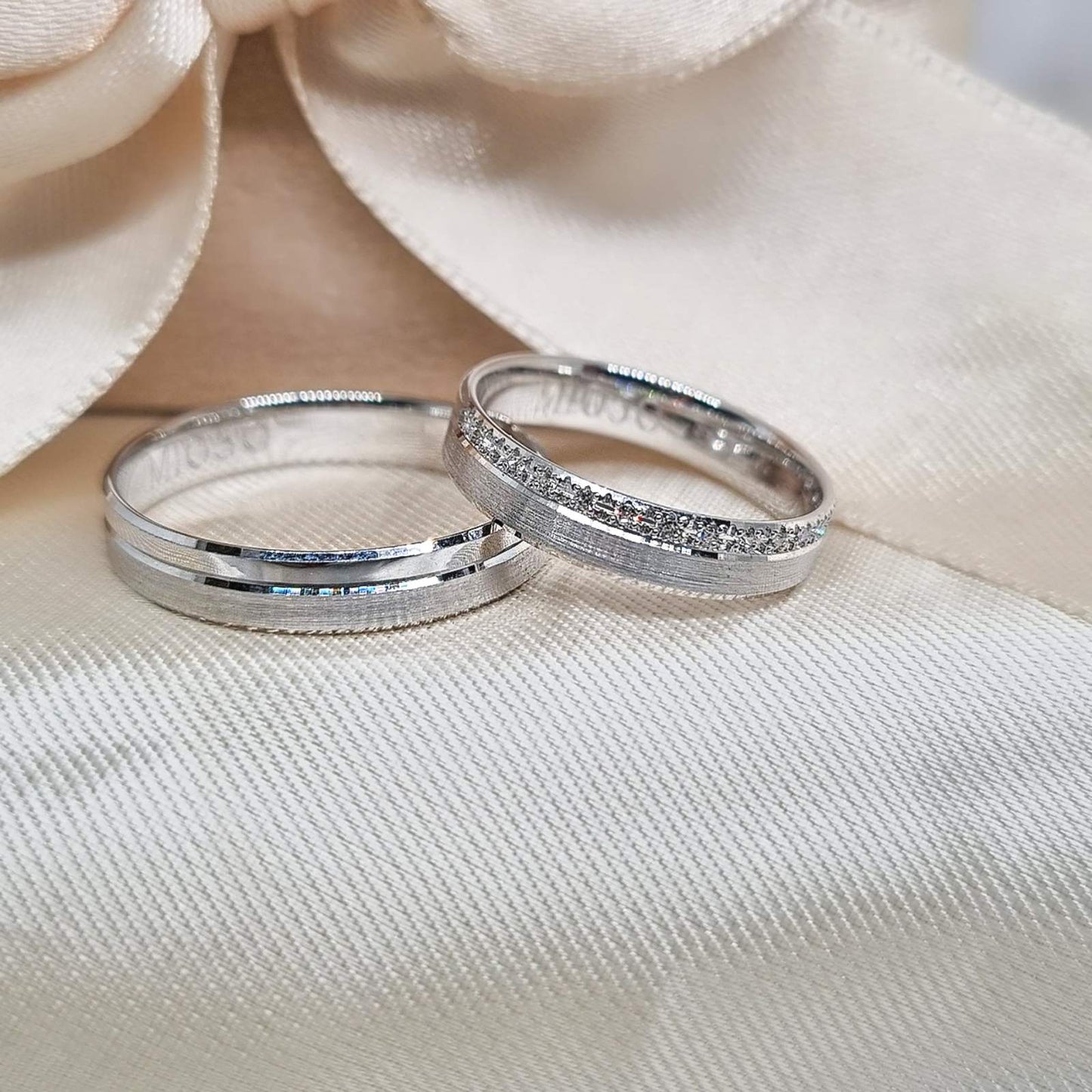 Burme od belog zlata sa ravnim ivicama, muška jednostavna i sjajna, dok je ženska ukrašena nizom cirkona duž centralne površine.