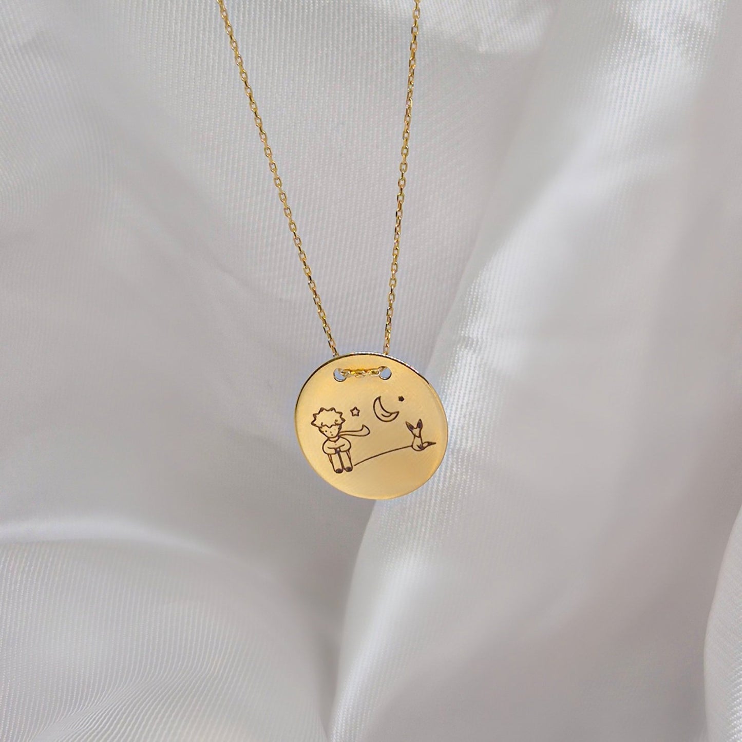 Zlatna ogrlica sa okruglim priveskom na kojem je ugraviran Mali Princ sa svojom ružom