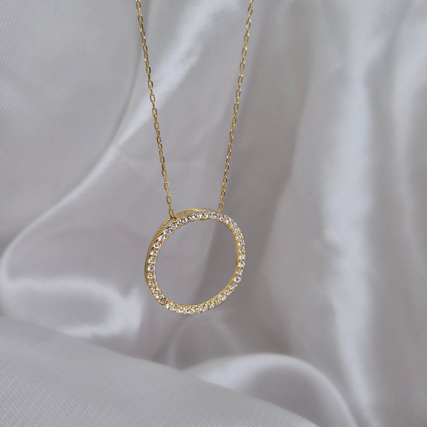 Zlatna 14-karatna oglica od žutog zlata sa priveskom u obliku kruga i cirkonima na njemu