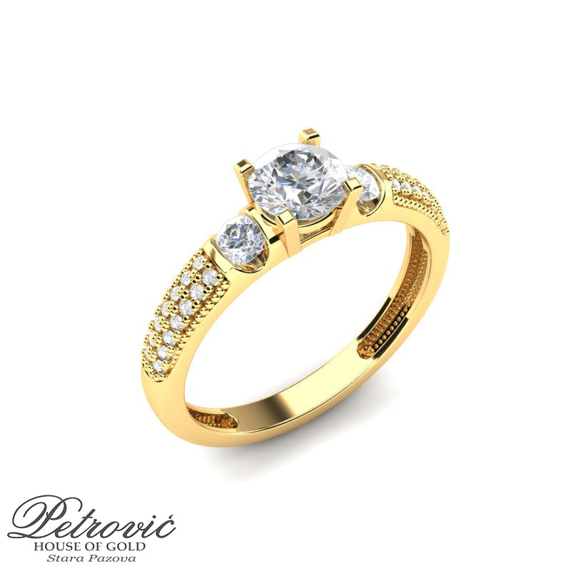 Verenički prsten izrađen od žutog zlata sa centralnim okruglim dijamantom i dva bočna dijamanta, ukrašen sitnim dijamantima duž obruča, prikazan iz kosog ugla na beloj pozadini.