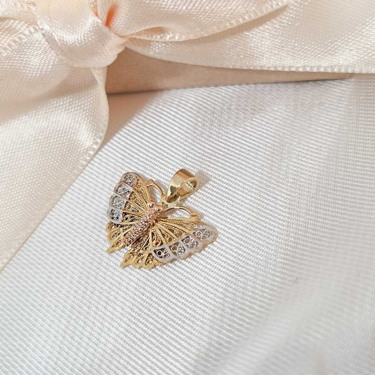 Zlatni privezak leptir na bež pozadini