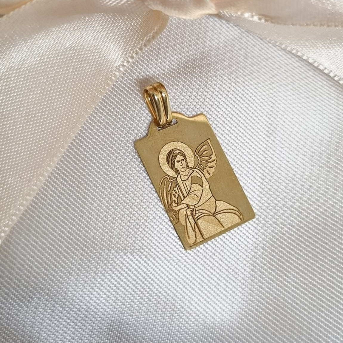 Zlatni privezak sa ugraviranim anđelom, pravougaonog oblika sa zaobljenim uglovima i sjajnom završnicom.
