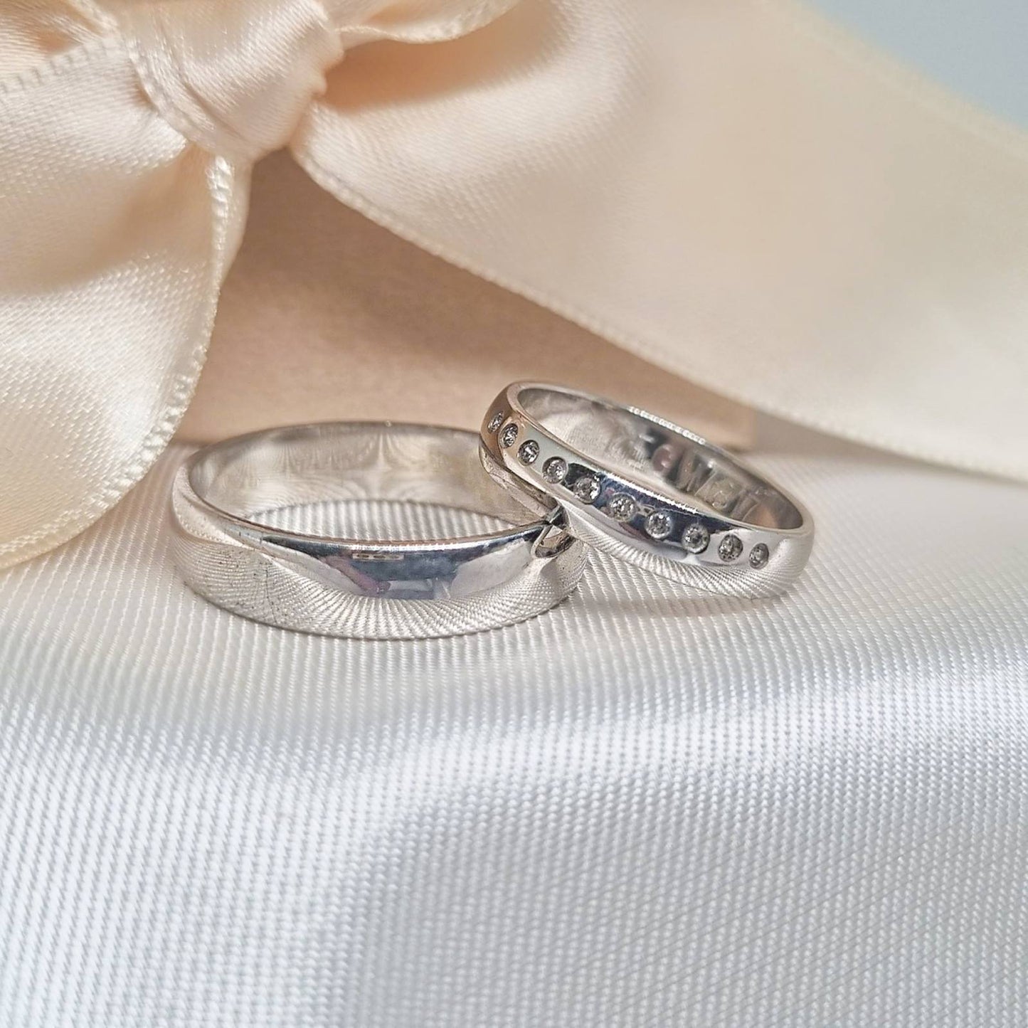 Burme od belog zlata na beloj tkanini – muška sa mat detaljima i ženska sa ugrađenim crnim cirkonima u ravnomernom nizu.