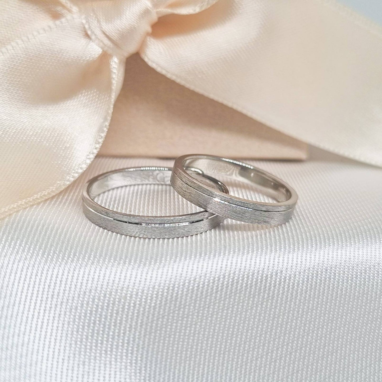 Burme od belog zlata sa kombinacijom mat i sjajne završne obrade, prikazane na beloj svilenoj podlozi.