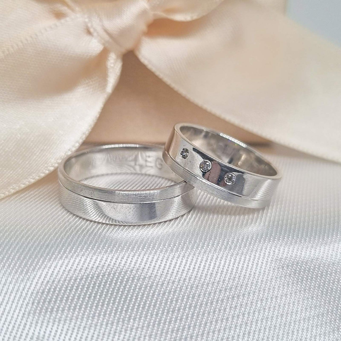 Zlatne burme sa matiranim i poliranim površinama, jedna sa jednostavnim dizajnom, a druga ukrašena sa tri cirkona, postavljene na bež tkanini sa svetlom pozadinom.