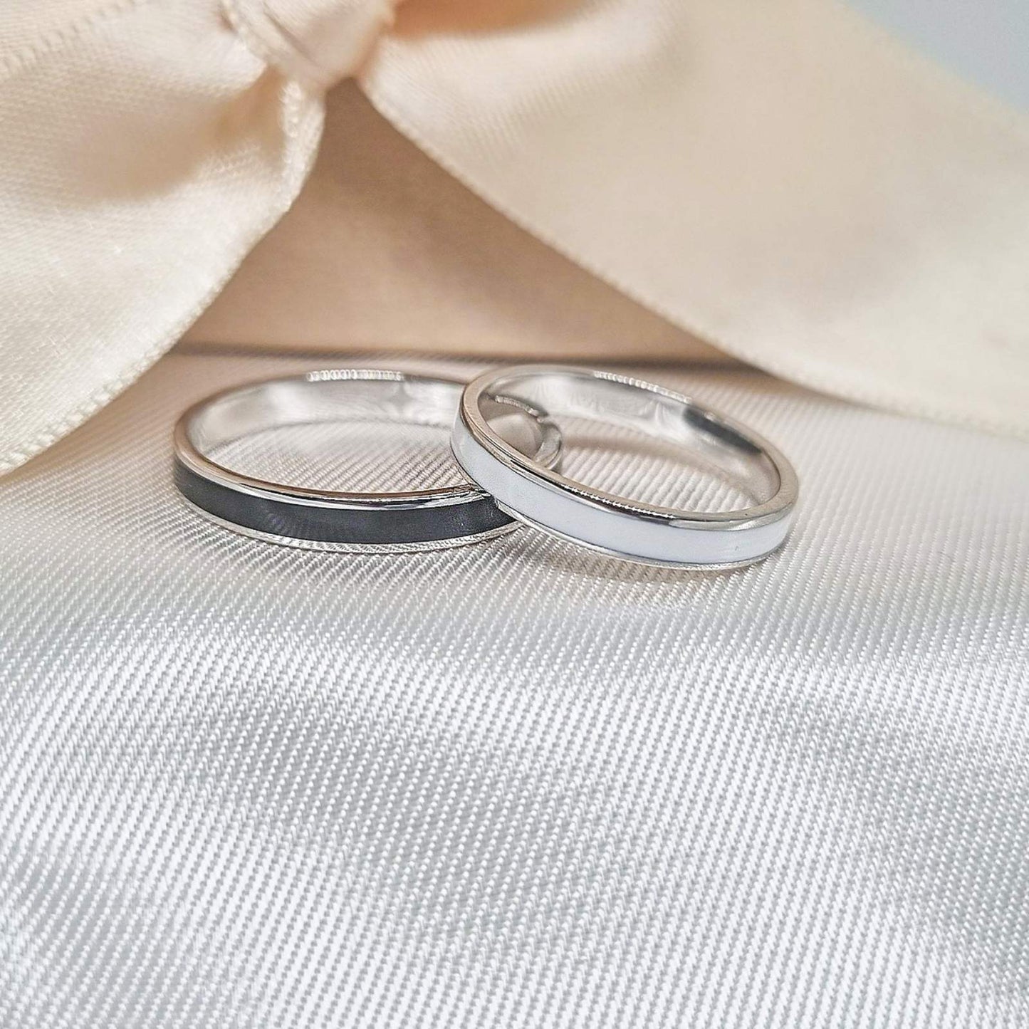 Zlatne burme sa kontrastnim crnim i belim detaljima, postavljene na bež tkanini sa svetlom pozadinom.