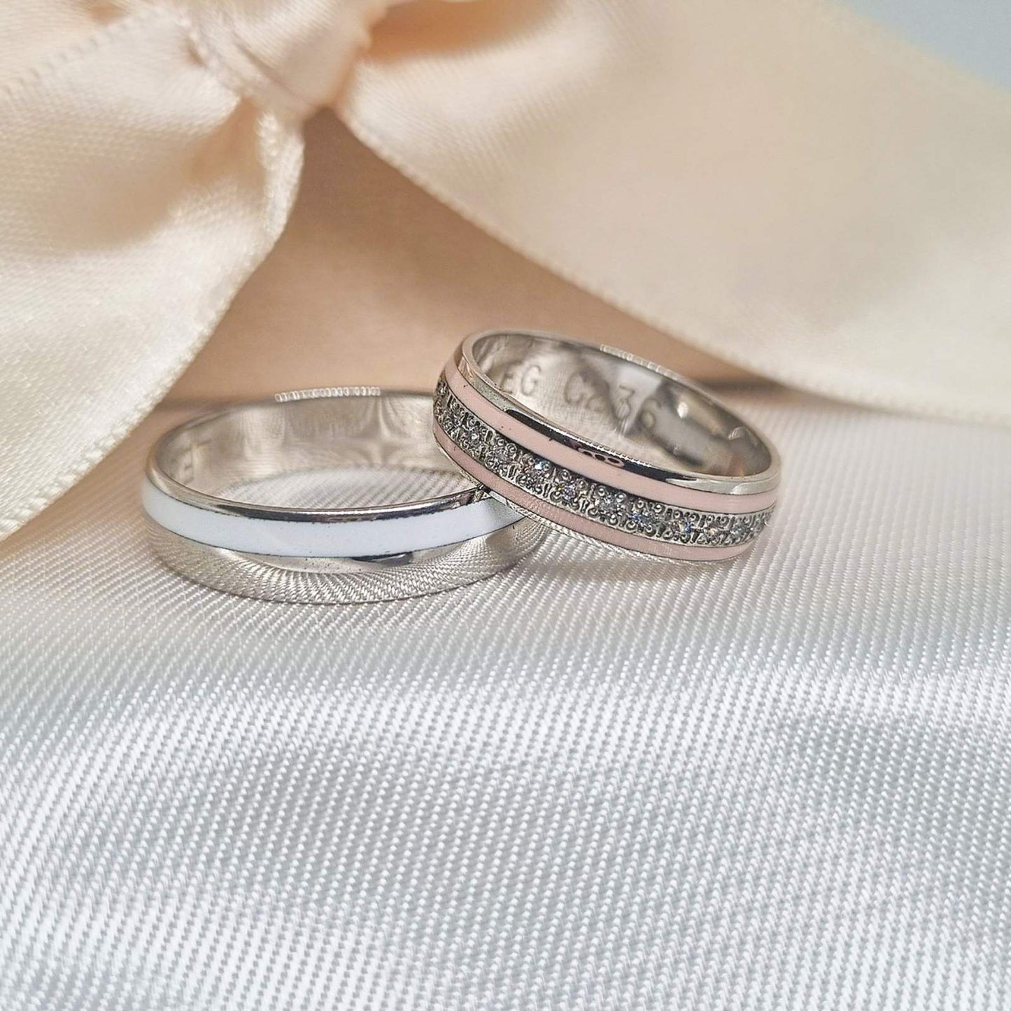 Zlatne burme sa kombinacijom belog i roze zlata, jedna polirana i druga ukrašena cirkonima, postavljene na bež tkanini sa svetlom pozadinom.