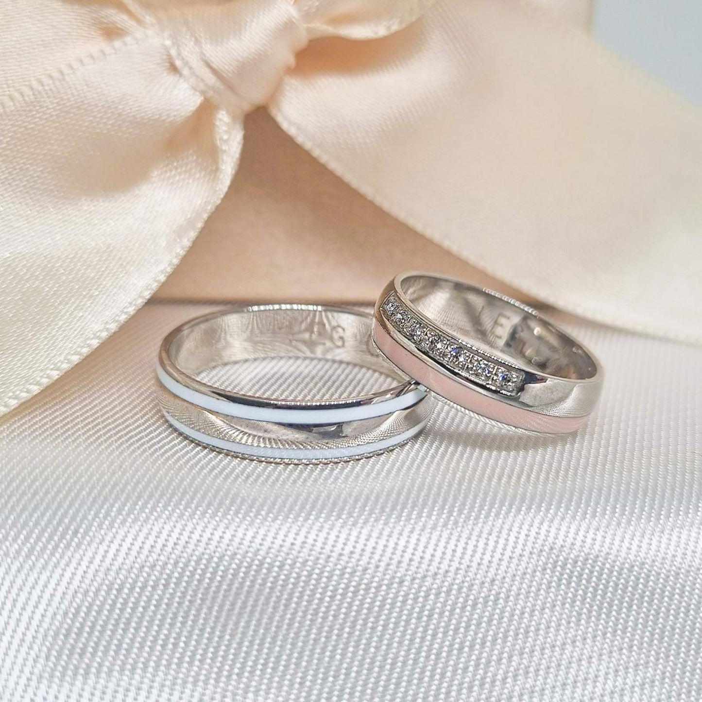 Burme od belog i roze zlata, jedna ukrašena cirkonima, prikazane na satenskoj podlozi ispred bež mašne.